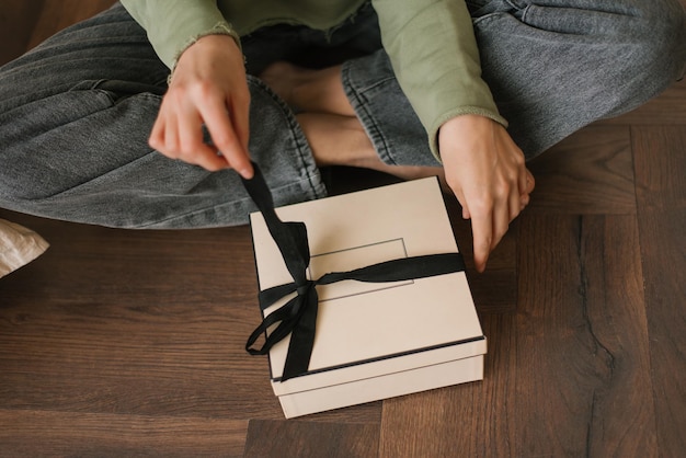 Closeup of female hands opening a gift box with a bow