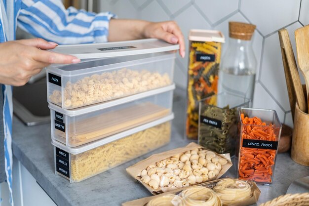 Closeup female hands placing and sorting pasta into pp boxes storage organization at kitchen