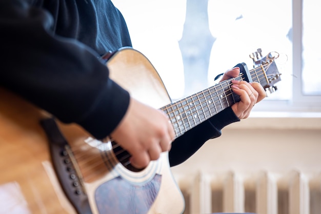 Mani femminili del primo piano che giocano una chitarra acustica