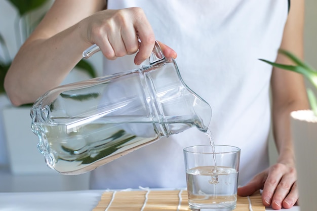 Closeup of female hands pouring drinking water into a glass morning rituals for health