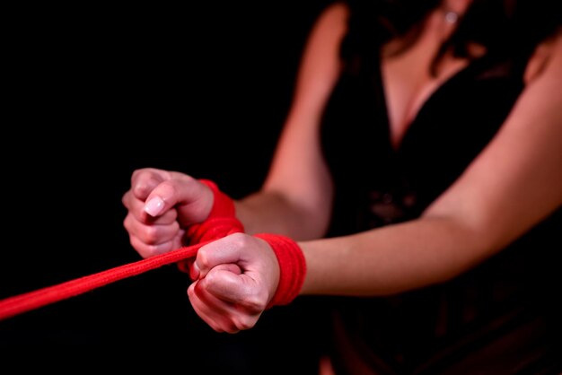 Closeup of female hands tied with a red rope Black isolated background Sex toys Sex shop Girl in sexy lingerie