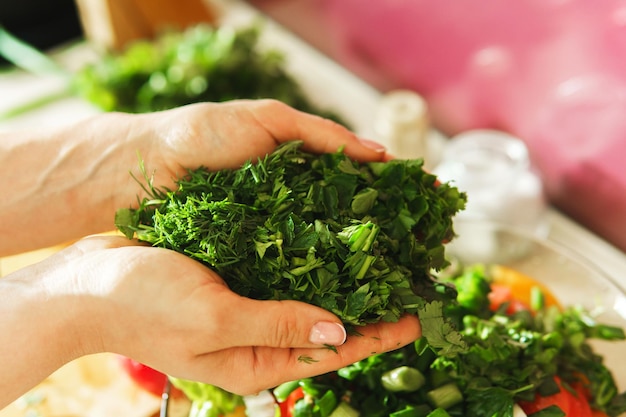 Closeup of female hands with chopped green dill and parsley