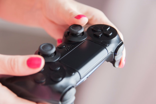 Foto primo piano delle mani femminili con gamepad durante il gioco