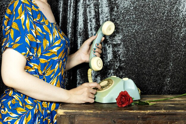 Closeup female hold an old and retro telephone headset on wood table girl hands with blue manicure