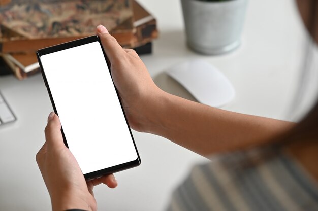 Above closeup female holding smartphone on table.