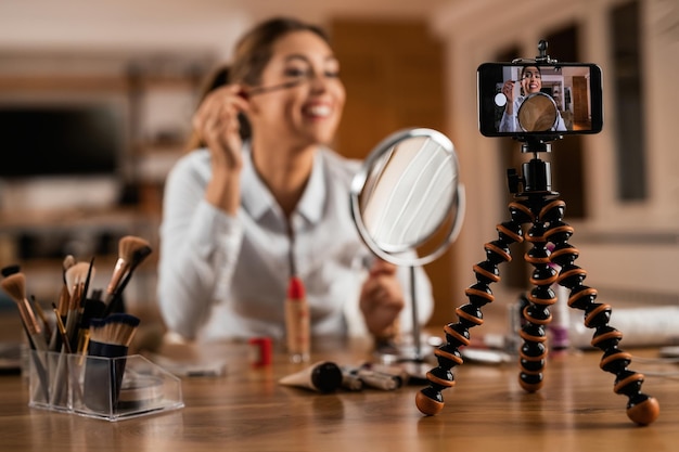 Primo piano dell'influencer femminile che usa il mascara mentre vlogging sul trucco a casa