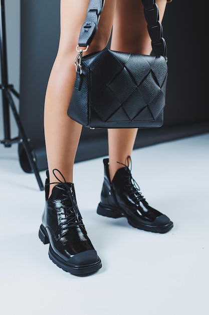Primo piano di gambe femminili in scarpe stringate in pelle nera borsa in pelle nera in mani femminili nuova collezione autunno di scarpe in pelle da donna 2022