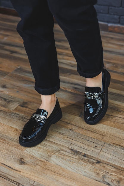 Closeup female legs in black trousers and leather black shoes Women's shoes in patent leather with a metal buckle New springsummer collection of women's leather shoes 2022