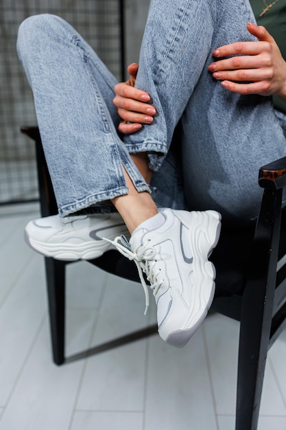 Closeup of female legs in jeans and shoes in fashionable sneakers closeup Women's everyday fashionable shoes