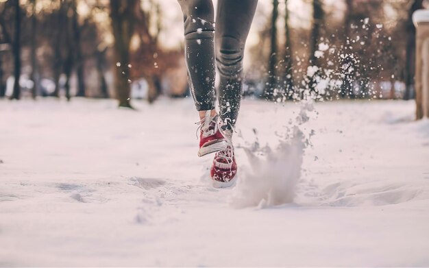 Closeup of female legs in sneakers running and kicking snow Snowy weather concept