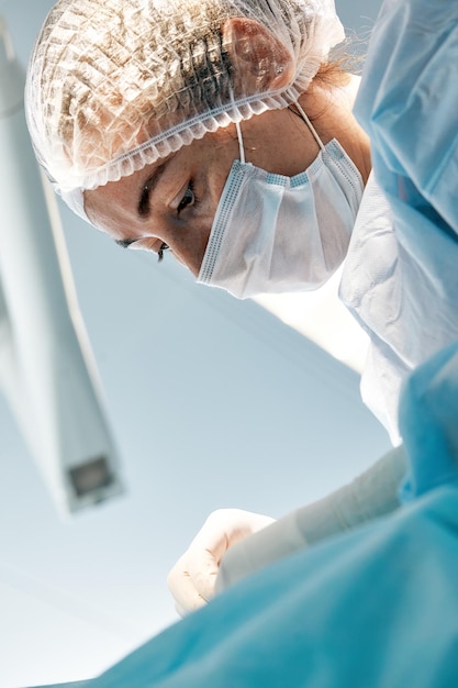 Foto primo piano di un chirurgo femminile in una sala operatoria un medico con un'espressione tesa sul viso in una sala operatoria