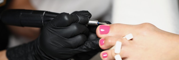 Closeup of female worker cleaning nail with special instrument professional nail master working