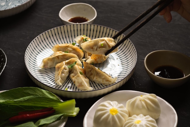 Closeup females hand using chopsticks with steamed Japanese veggies dumplings and vegan buns