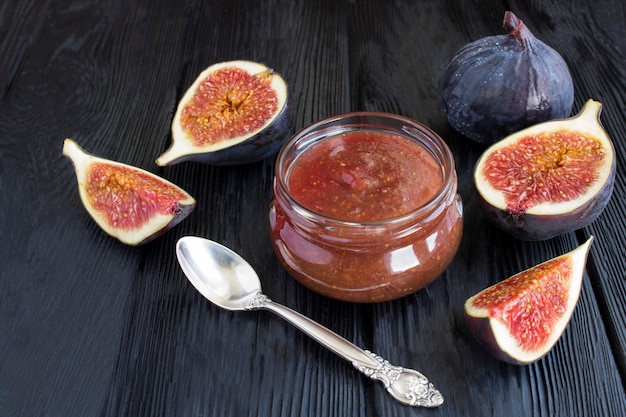 Closeup on fig jam in the glass jar on the black wooden table