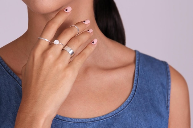 Closeup of the fingers of a woman's hand with several silver rings and beautiful manicure