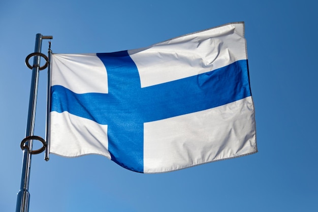 Closeup on a Finnish flag waving atop of its pole