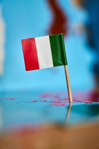 Closeup of a flag of Italy with a small stick on the map