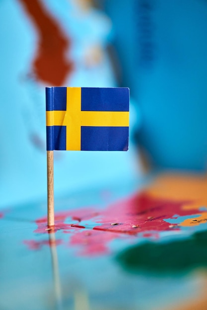 Photo closeup of a flag of sweden with a small stick on the map