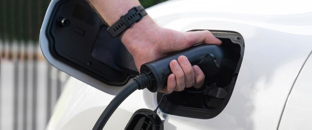 クローズ アップ フォーカス手挿入充電ステーションから電気自動車への EV 充電プラグ 進歩的な代替クリーン エネルギー エンジン車技術環境に優しい輸送のアイデアのための再生可能な EV 車