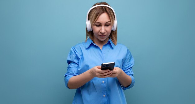 Closeup of a focused millennial freelancer woman in a casual shirt with big white headphones holding