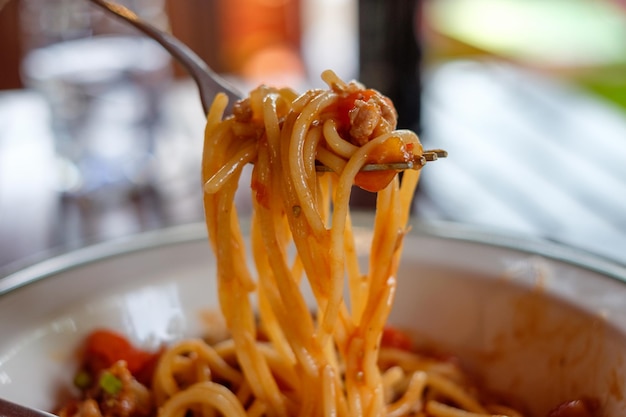 Closeup fork scooping spaghetti pork sauce