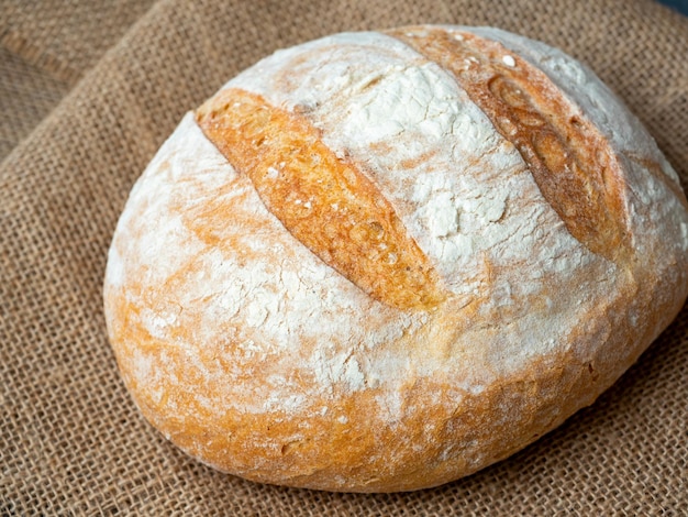 Primo piano di pane di frumento rotondo croccante fresco su sfondo scuro vista dall'alto piatto