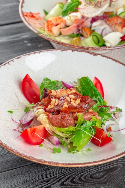 Closeup of a fresh green salad with sliced seared tenderloin steak