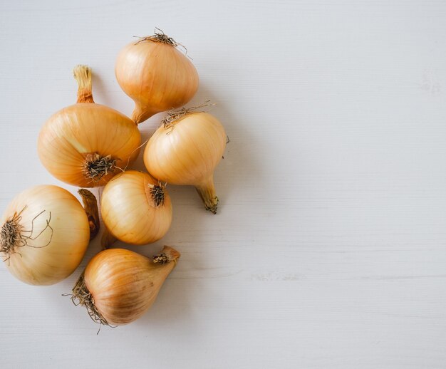 Closeup of fresh onions on white wooden surface.