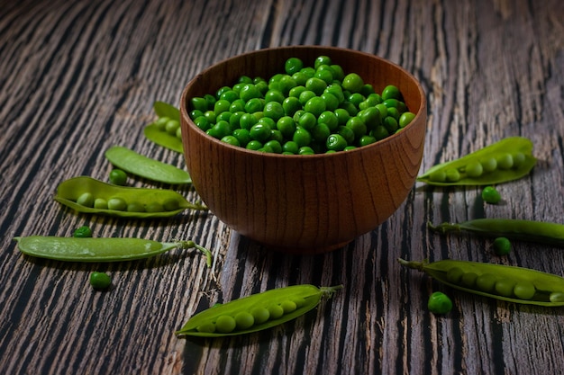 Closeup of fresh peas in a bowl and wooden background Healthy food concept