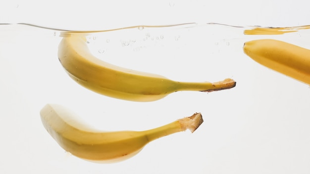 Closeup of fresh ripe bananas falling and splashing in water