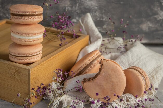 Closeup of the fresh sweet macaroons on the white fabric with decorative flowers