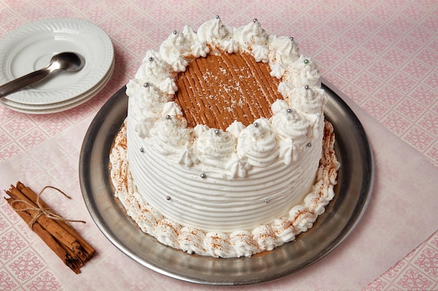 Primo piano di una torta fatta in casa saporita fresca decorata con panna montata bianca e cannella