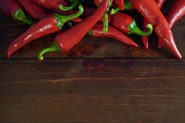 Closeup fresh wet red chili peppers on wooden table