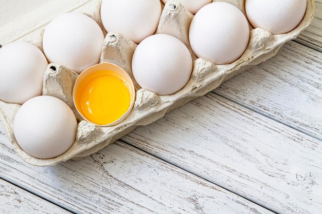 Closeup of fresh white organic chicken eggs in the paper tray and egg yolk