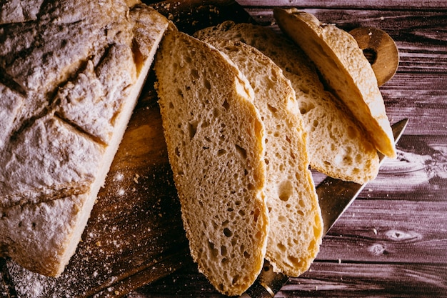 Closeup of freshly cut slices of homemade bread last on a cutting board with a knife on a table