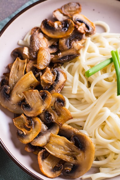 Closeup of fried mushrooms and noodles vertical view