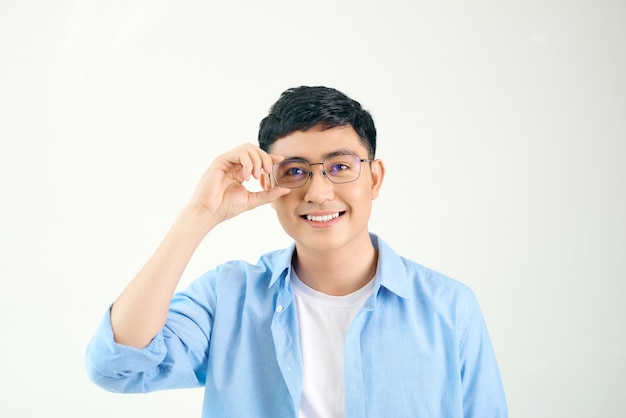 眼鏡をかけているフレンドリーな男のクローズアップ。眼鏡を調整し、レンズを通して見つめている若いアジア人男性。視力と目のケアの概念