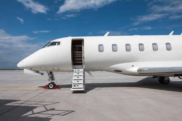 Closeup of the front of the modern white private jet with an opened gangway door