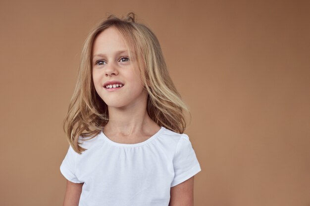 Closeup front portrait of adorable little girl with wavy blond hair, dressed in white clothes  Copy space.