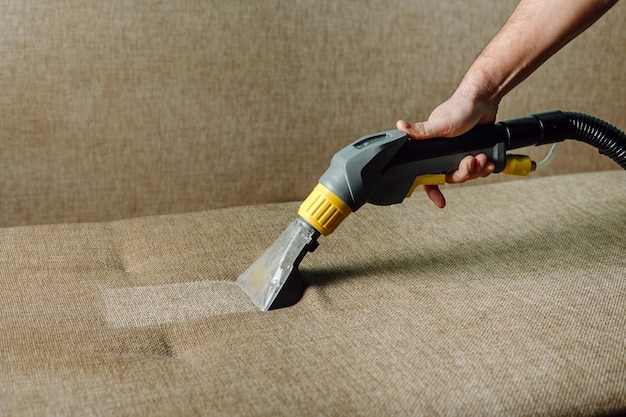 Closeup of a furniture vacuum cleaner and a dirty sofa Cleaning and house cleaning housekeeper