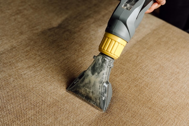 Closeup of a furniture vacuum cleaner and a dirty sofa Cleaning and house cleaning housekeeper