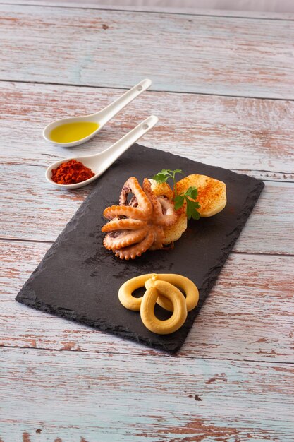 Closeup of Galician style octopus on a black slate plate Typical Spanish food