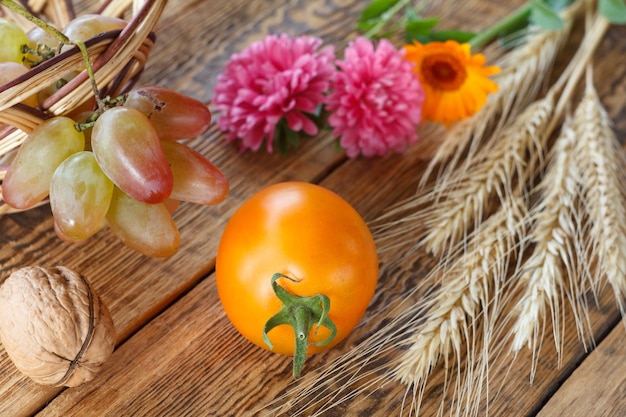 Closeup gele tomaat walnoten druif tarwe oor calendula bloem en rieten mand