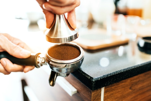 Closeup gemalen koffieboon in metalen filter met handvat houden door vrouw hand