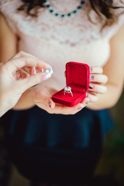 Foto primo piano di una ragazza che tiene la fede nella scatola rossa, gioielli di nozze