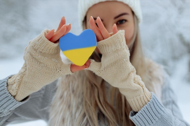 Closeup girl holds a snowy heart in front of her in gloves