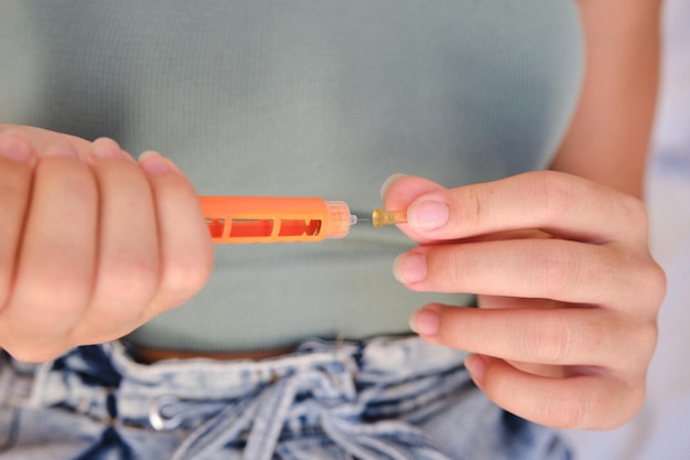 Closeup of a girl using an insulin pen to inject insulin at home