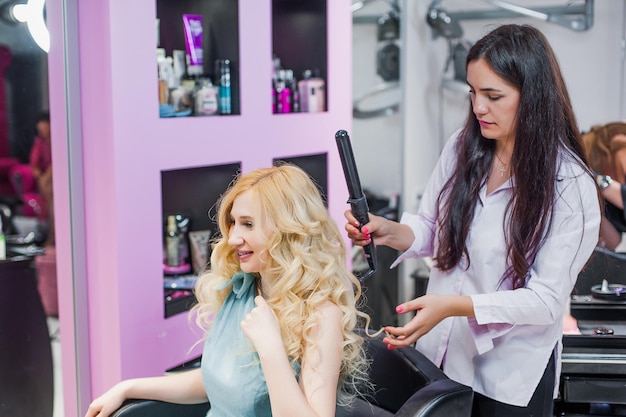 Primo piano di una ragazza con le mollette sulla testa il maestro fa lo styling dei capelli