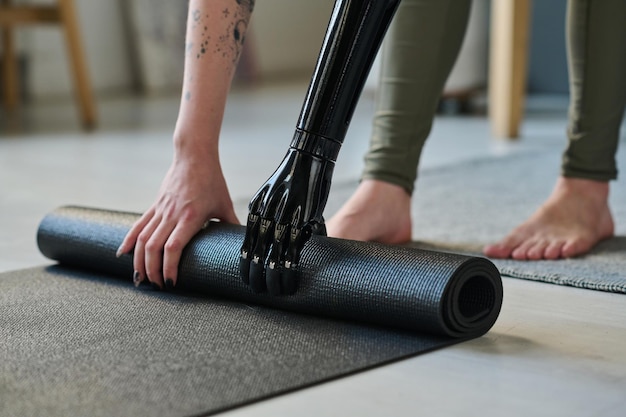 Closeup of girl with disability preparing exercise mat on the floor for sport exercises