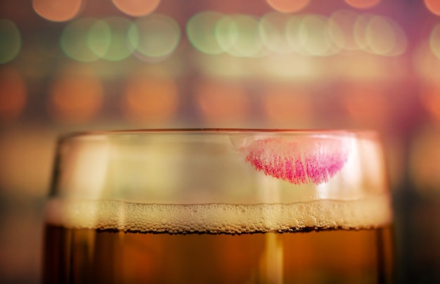 Closeup of Glass of Beer with Red Lipstick Mark in Bar or Restaurant. Feminine Mood